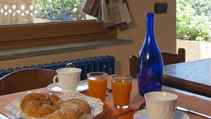 A breakfast table with croissants, orange juice, and a blue bottle. - Miramonti (Valtournenche)