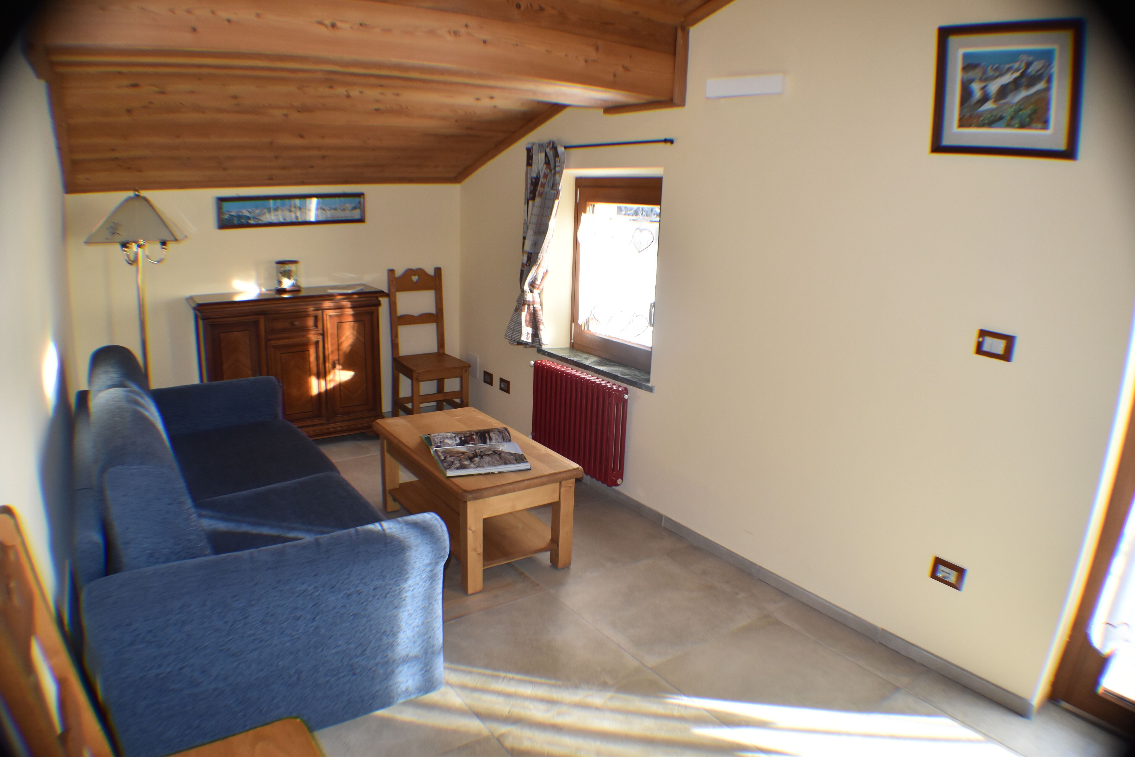 Salón con sofá azul, mesa de madera y ventana con vistas.