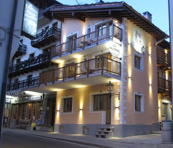 Un hotel de varios pisos con balcones, un cartel que dice 'Bar Glacier Gherillon' y un letrero 'Mirandotti' en la fachada.