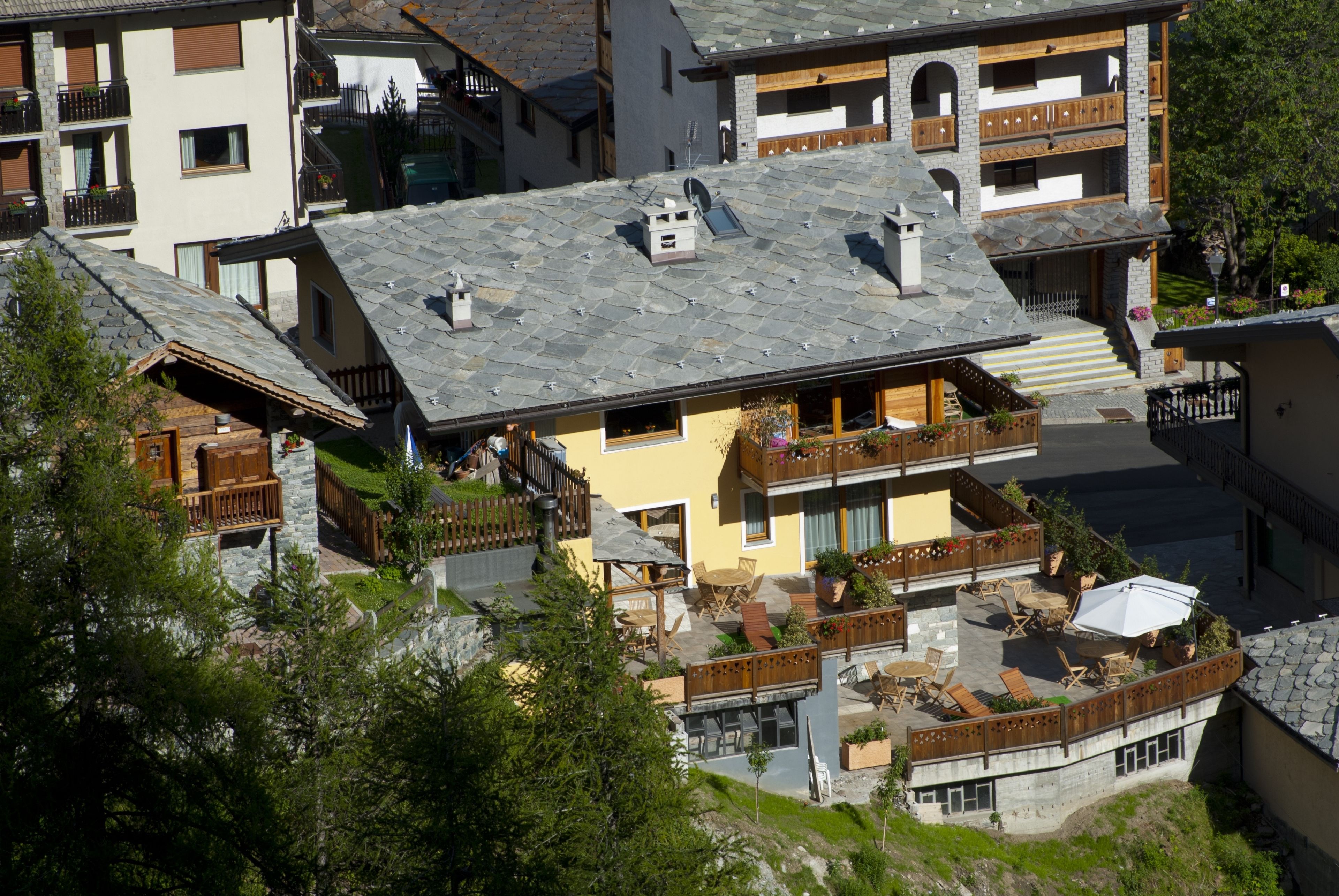 A multi-story building with a stone roof, balconies with wooden railings, and outdoor seating areas.
