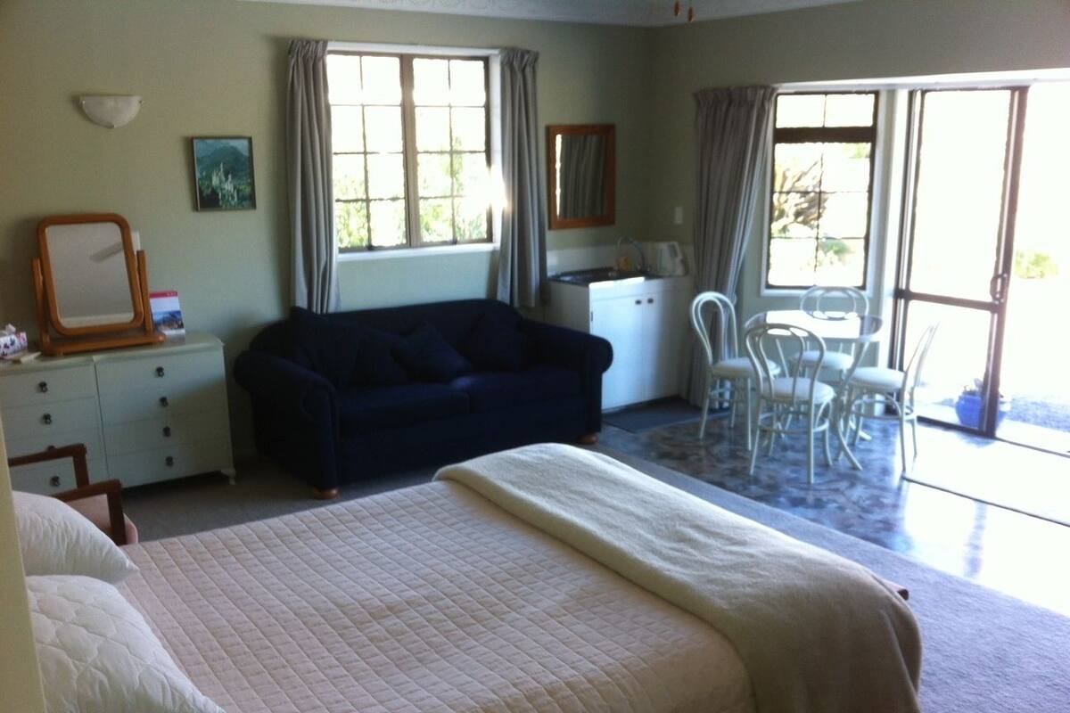 A bedroom with a bed, a sofa, a desk, and a chair.