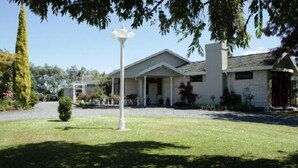 A two-story house with a front porch, a lawn, and a street lamp. - Somersal Bed & Breakfast (Pirongia)