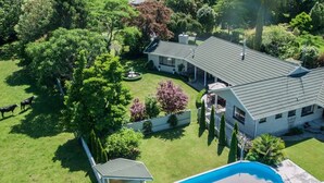A large house with a swimming pool, surrounded by a well-maintained lawn and trees. - Somersal Bed & Breakfast (Pirongia)