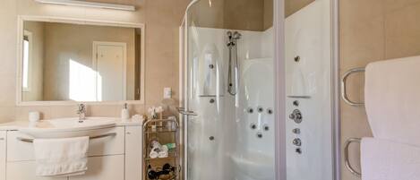 A modern bathroom with a glass-enclosed shower, a sink with a mirror, and a towel rack.