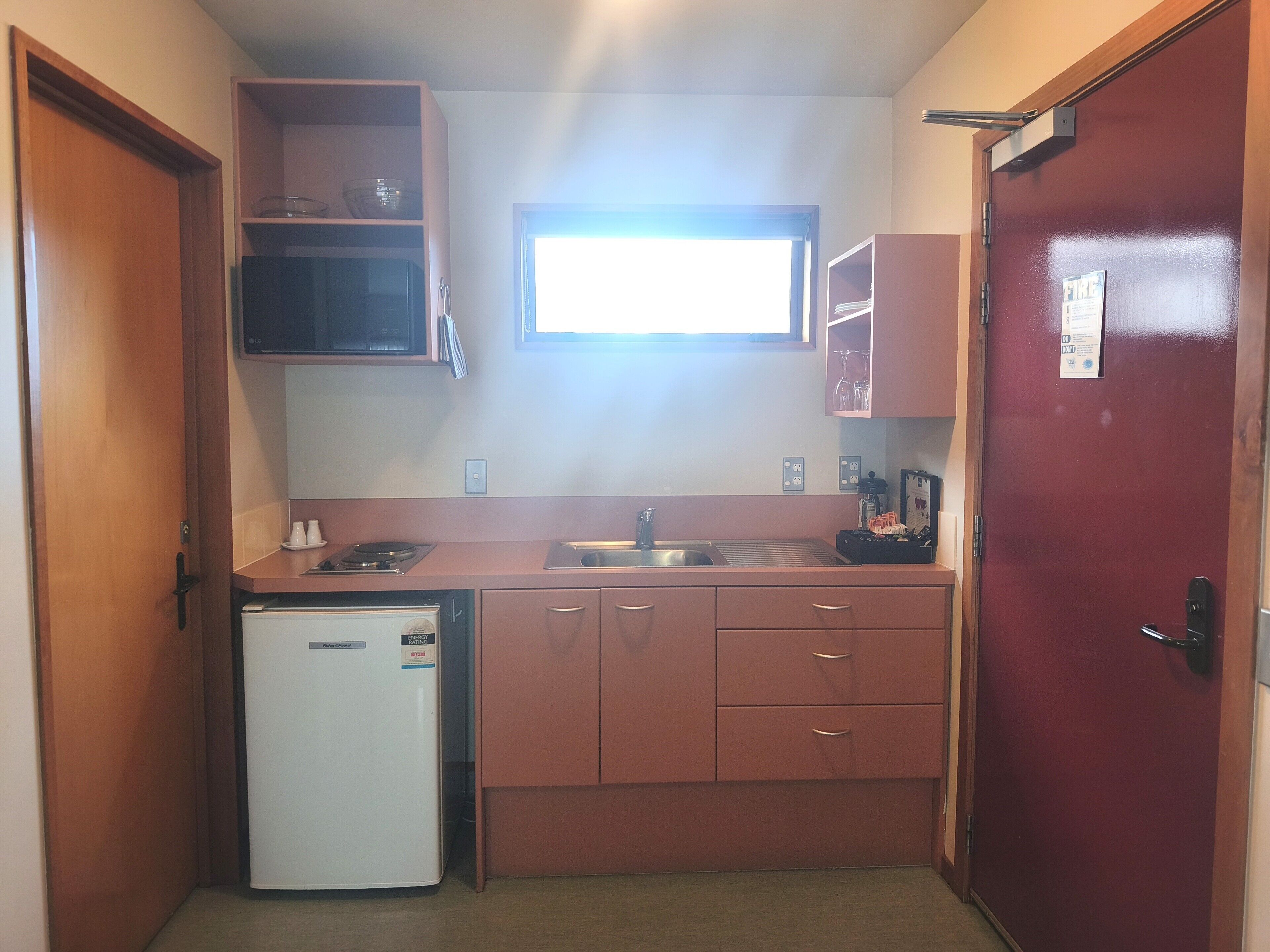 A compact kitchenette with a refrigerator, microwave, sink, and cabinets.