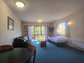 Una habitación con cama, sofá, mesa y televisión.