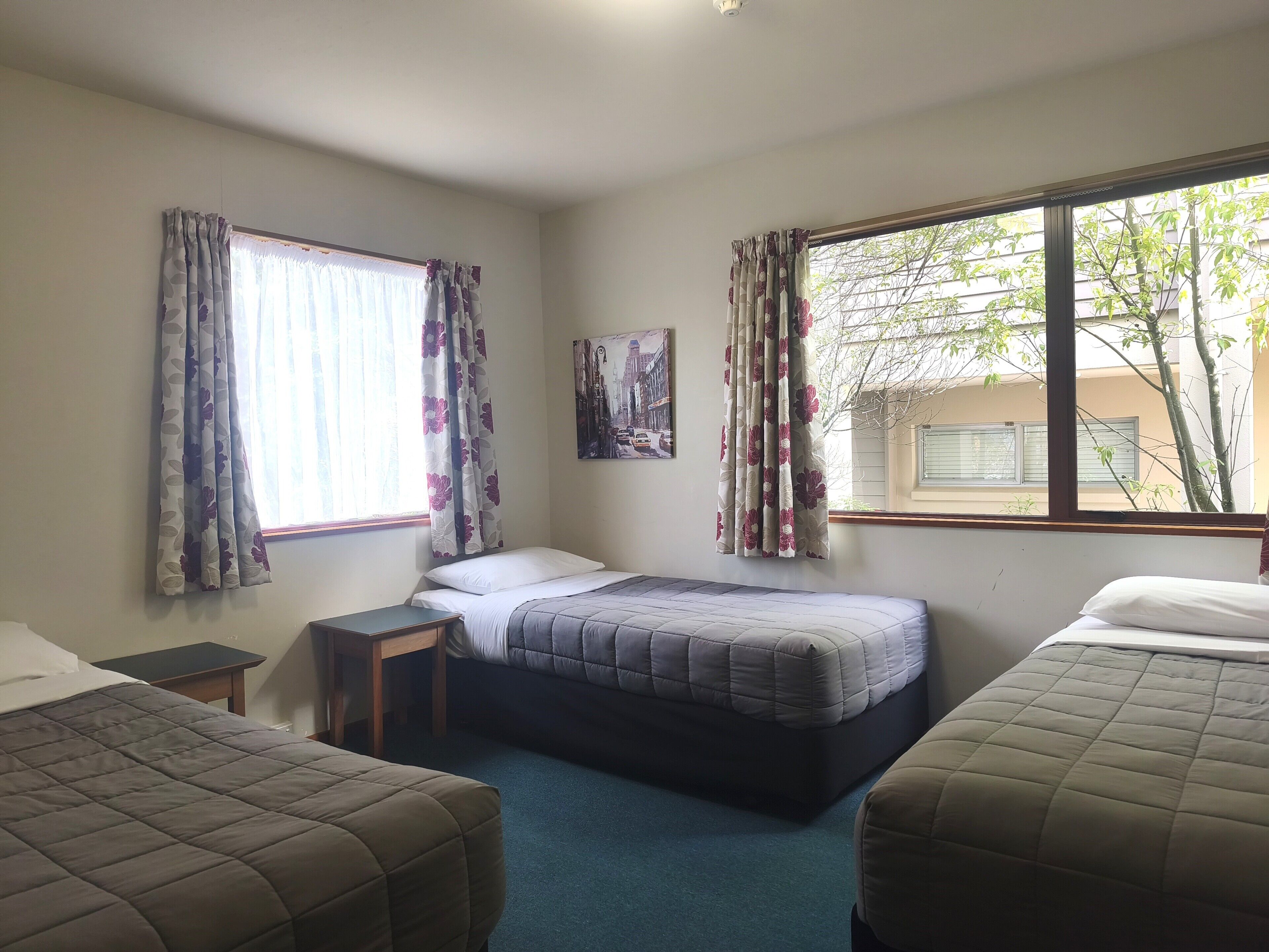 A room with two beds, a small table, and a window with curtains.
