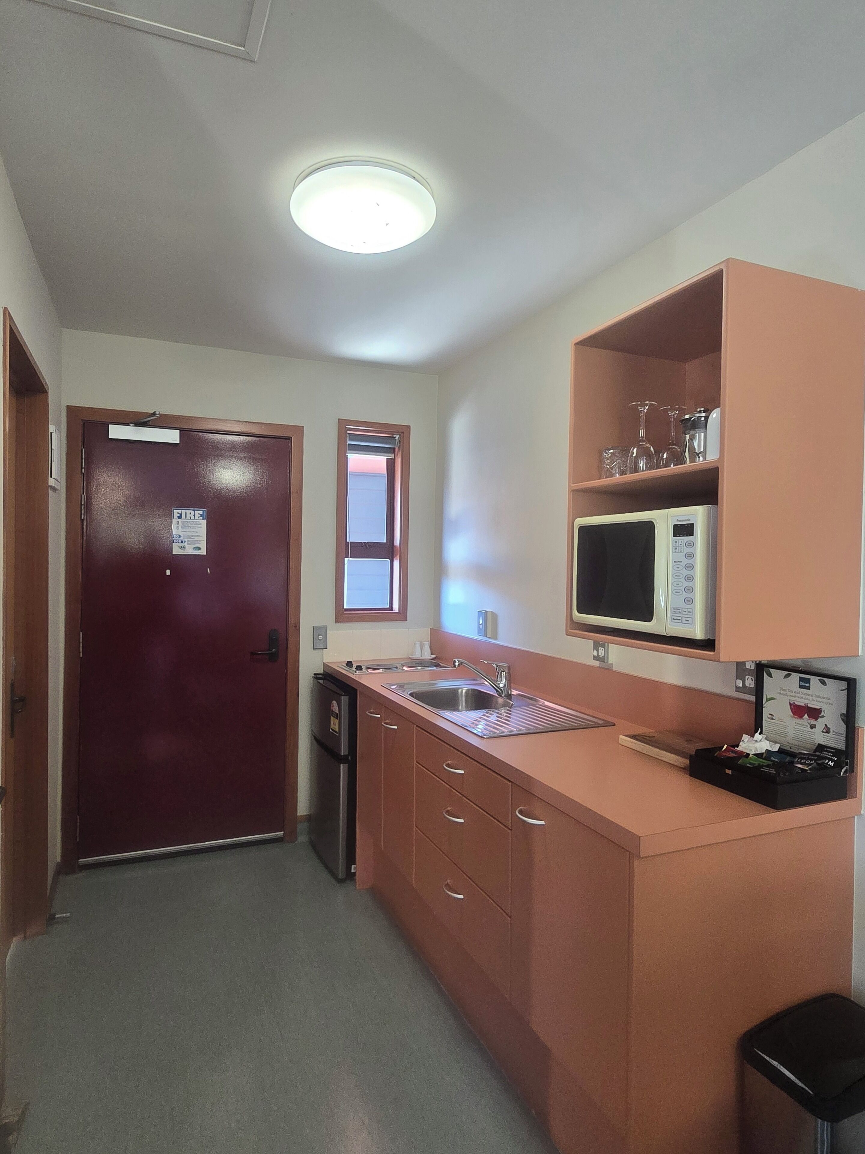 Cocina compacta con microondas, fregadero y un refrigerador pequeño.