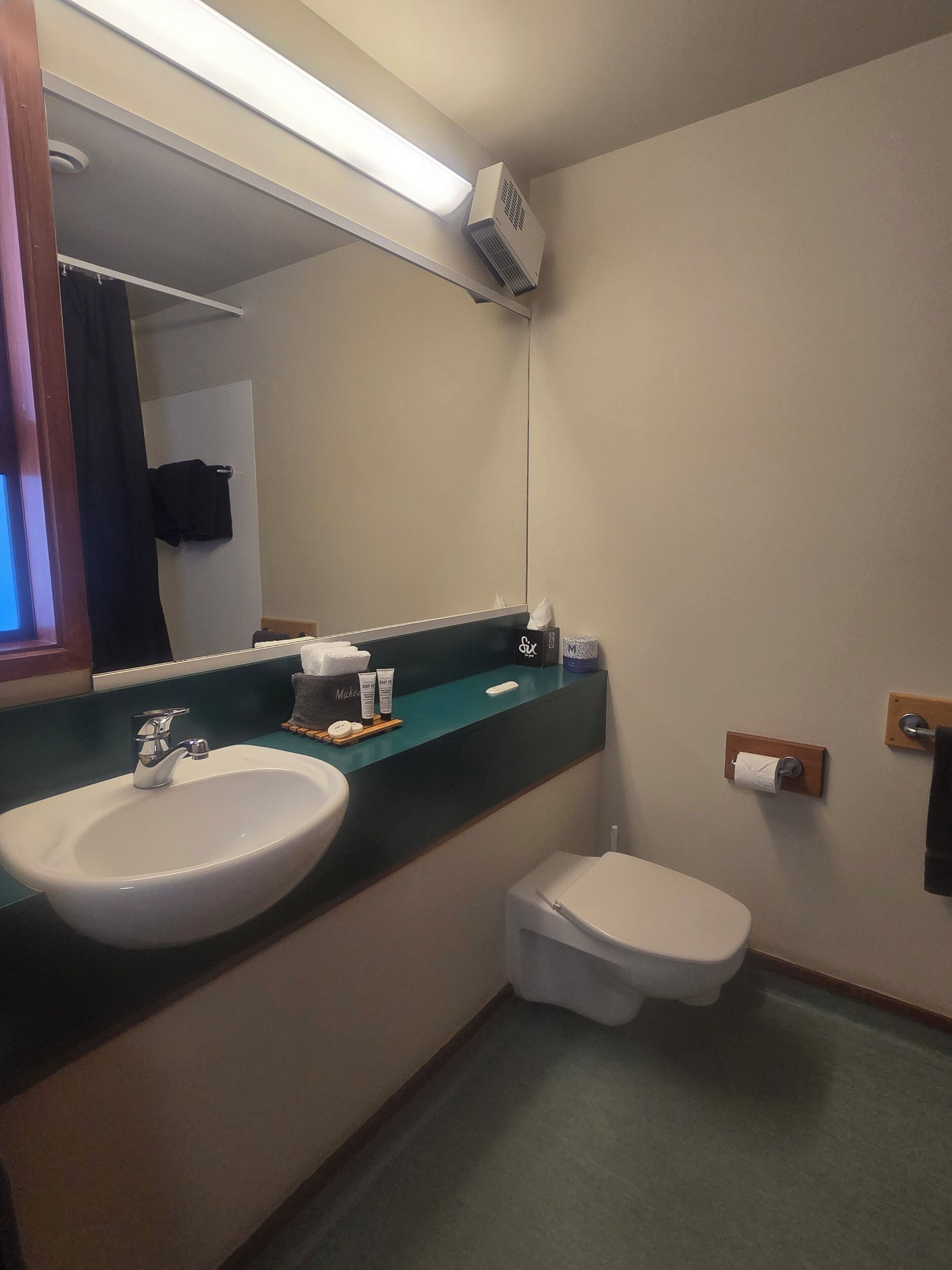A bathroom with a sink, toilet, and a mirror.