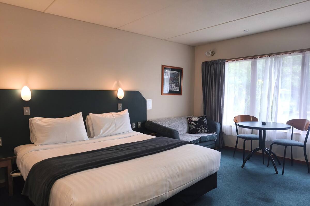 Una habitación de hotel con una cama, un sofá, una mesita y sillas.