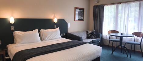 A hotel room with a bed, a sofa, a small table, and chairs.