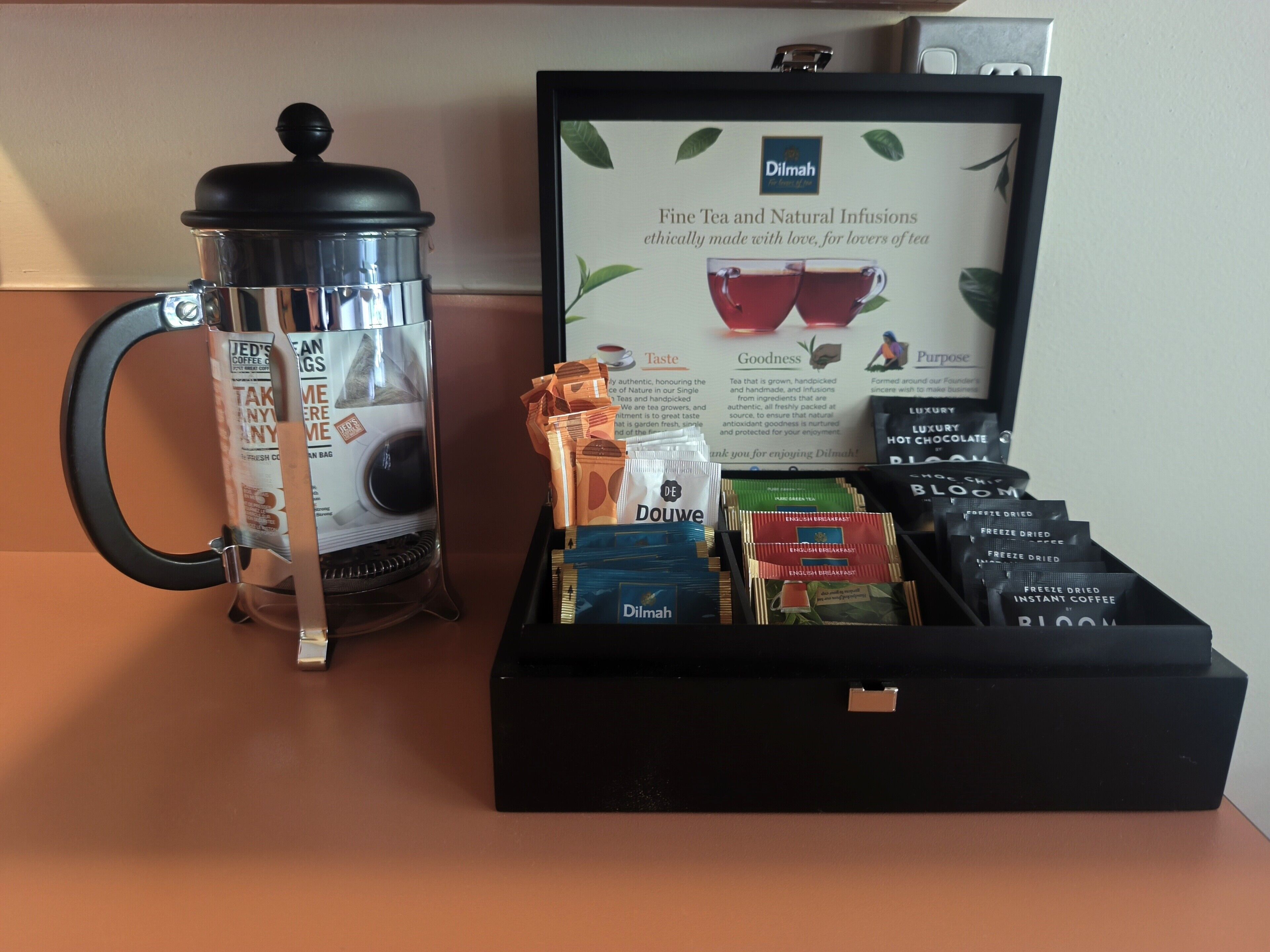 A coffee maker, a framed product brochure, and a box of tea and coffee products.