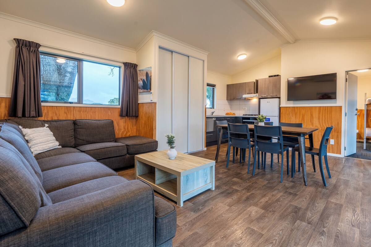 A modern living room with a sectional sofa, a wooden coffee table, and a dining area with a table and chairs.