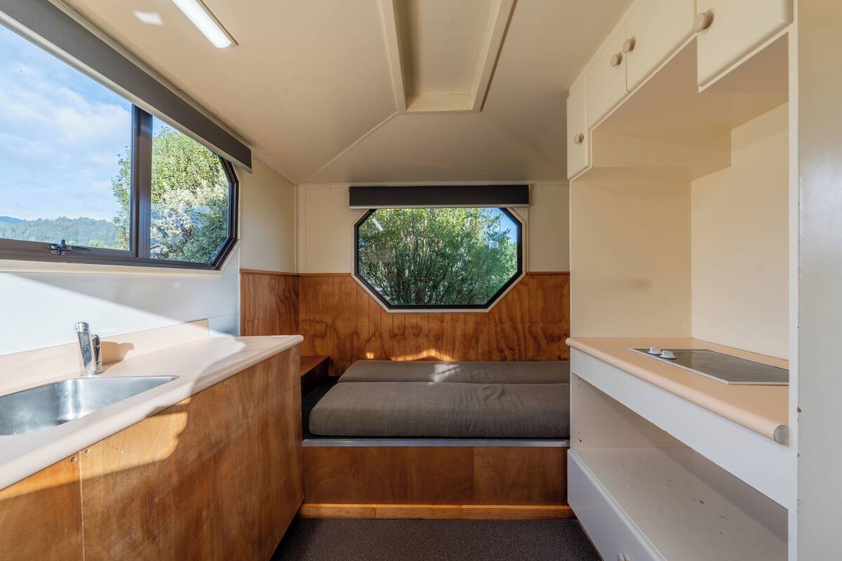 A compact kitchenette with a window, a sink, and a bench.