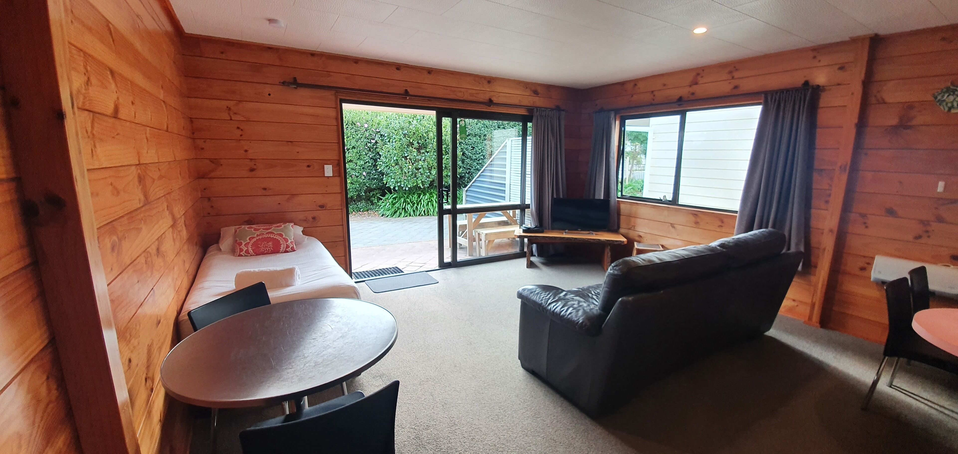 Et hyggeligt rum med seng, sofa, lille bord og fjernsyn.