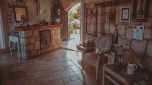 A rustic interior with a stone wall, a wooden counter, and a chair. - Chigdem Hotel - Special Class (Cesme)