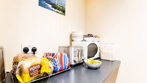 A kitchen counter with a loaf of bread, a toaster, a kettle, and a bowl of cereal. - Lost Guest House - Aberdeen (Aberdeen)