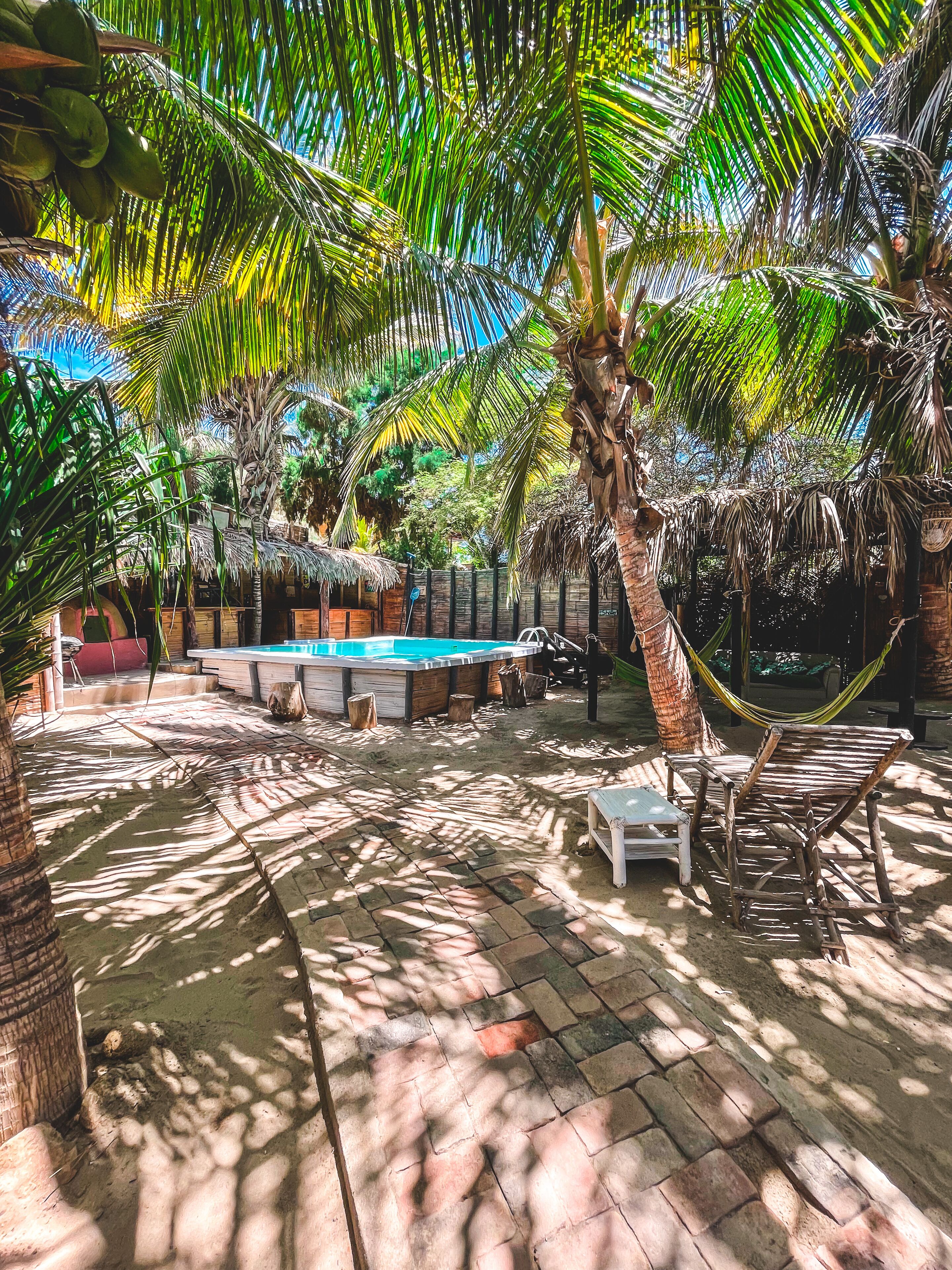 A pool area with a hammock, lounge chairs, and a thatched-roof structure.