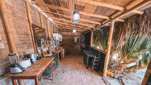 Uma cozinha rústica com piso de tijolos, móveis de madeira e telhado de colmo.