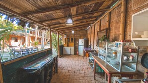 Um interior rústico com telhado de palha, móveis de madeira e uma vitrine de vidro.