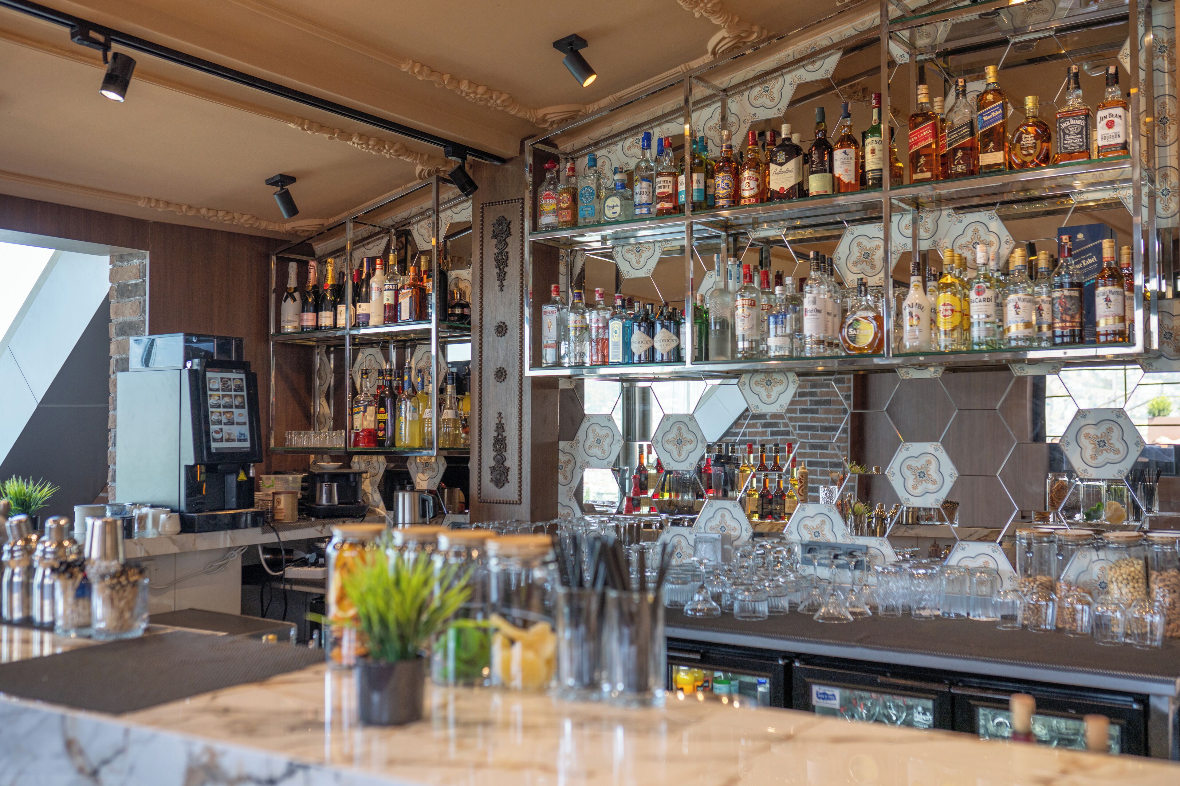 A bar area with shelves of liquor bottles, glasses, and a cash register.