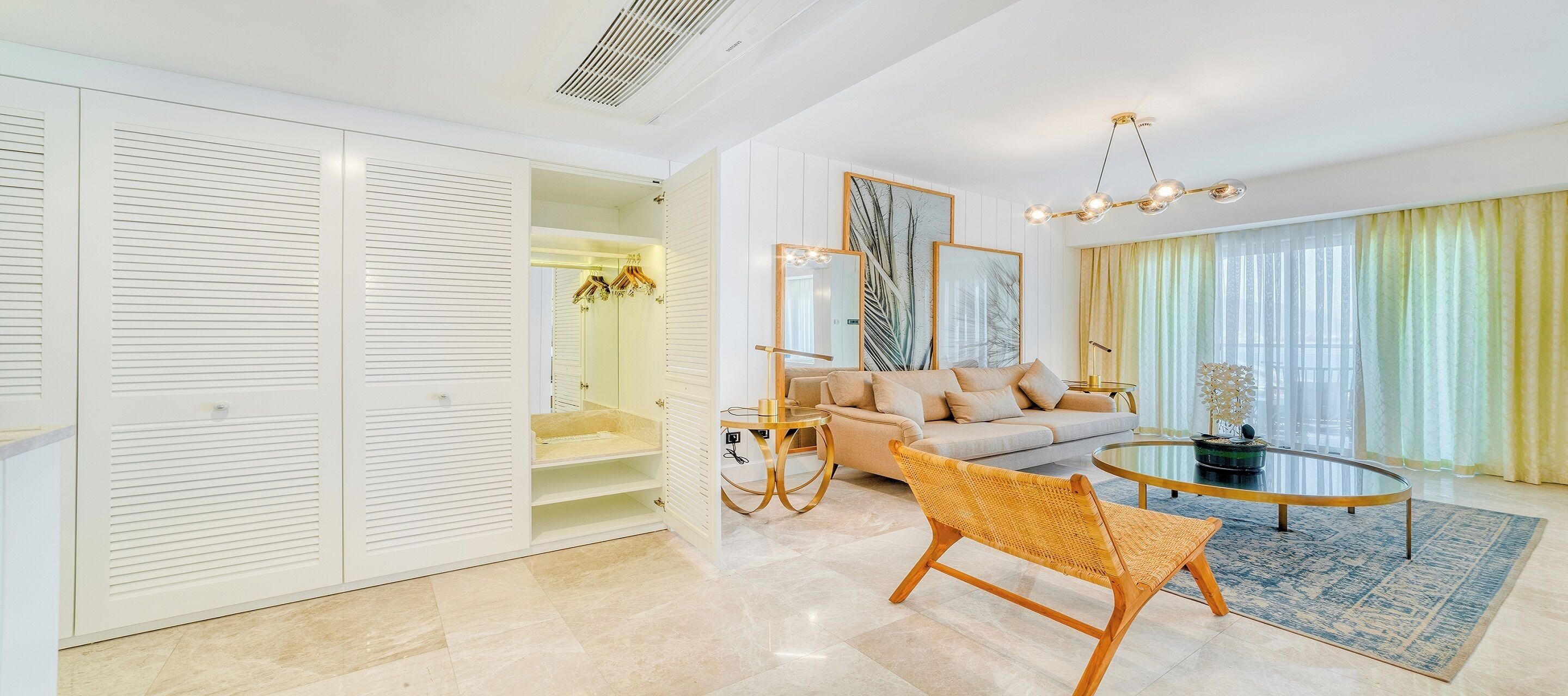 A modern living room with a sofa, a wicker chair, a glass coffee table, and a large mirror.