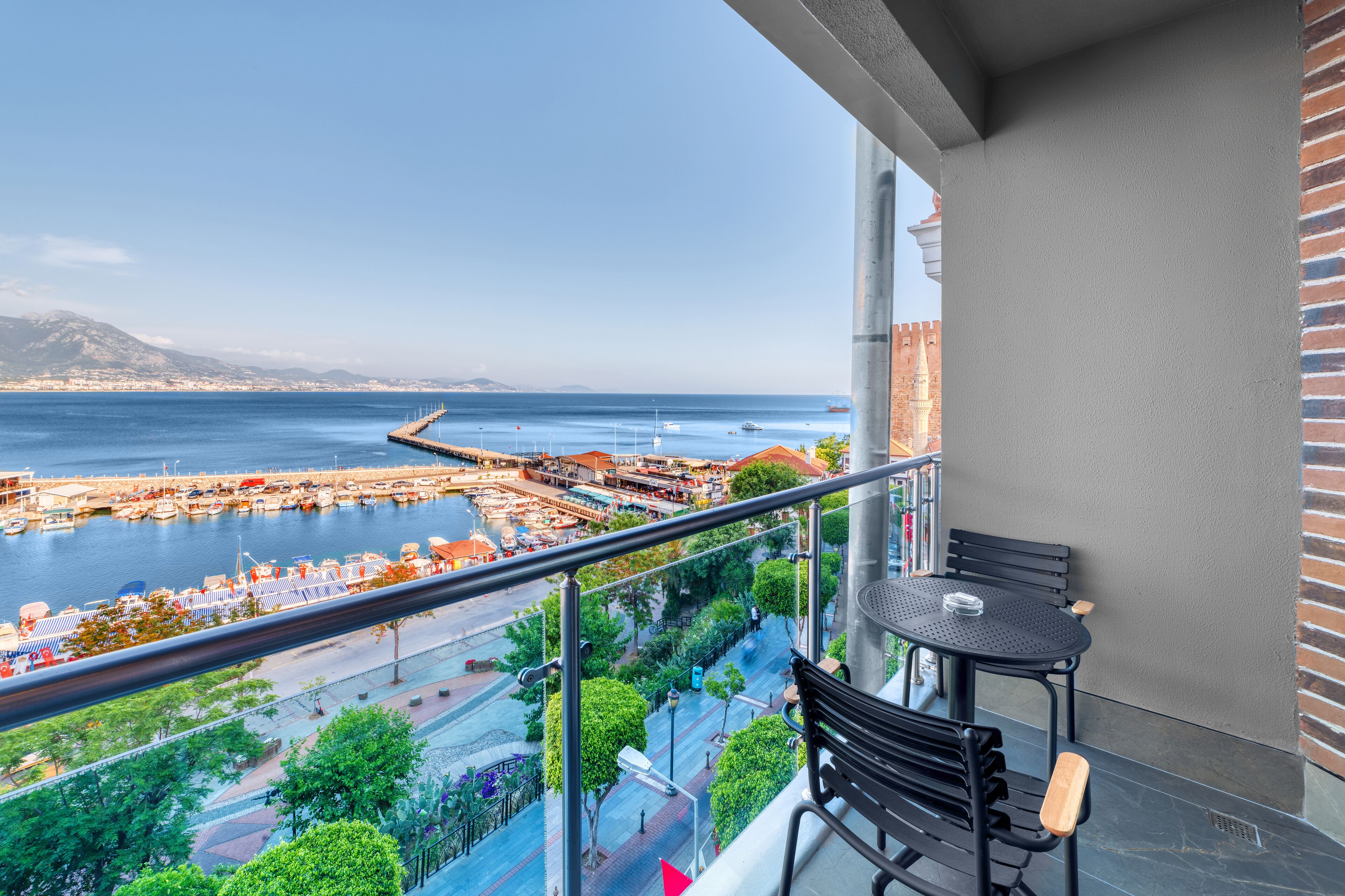 En balkon med udsigt over en lysthavn og havet.