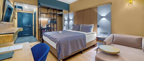 A modern hotel room with a bed, a sofa, a desk, and a wardrobe.