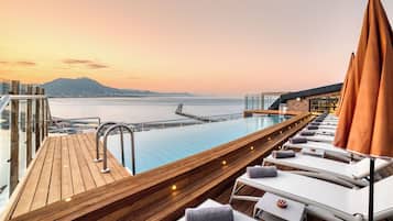 Una piscina al aire libre, sombrillas, sillones reclinables de piscina
