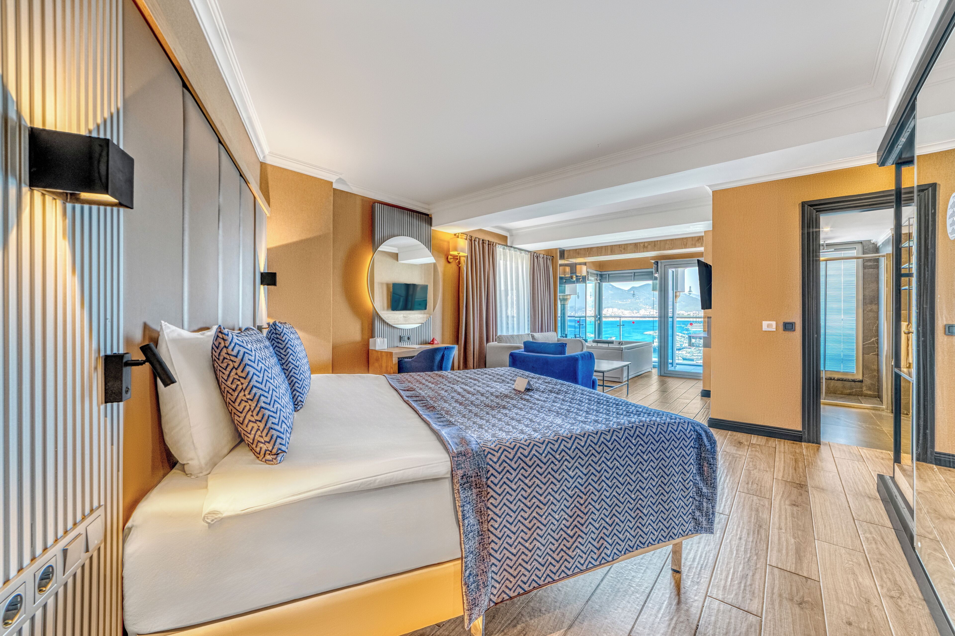 Ett modernt hotellrum med en stor säng, ett skrivbord och utsikt över havet.