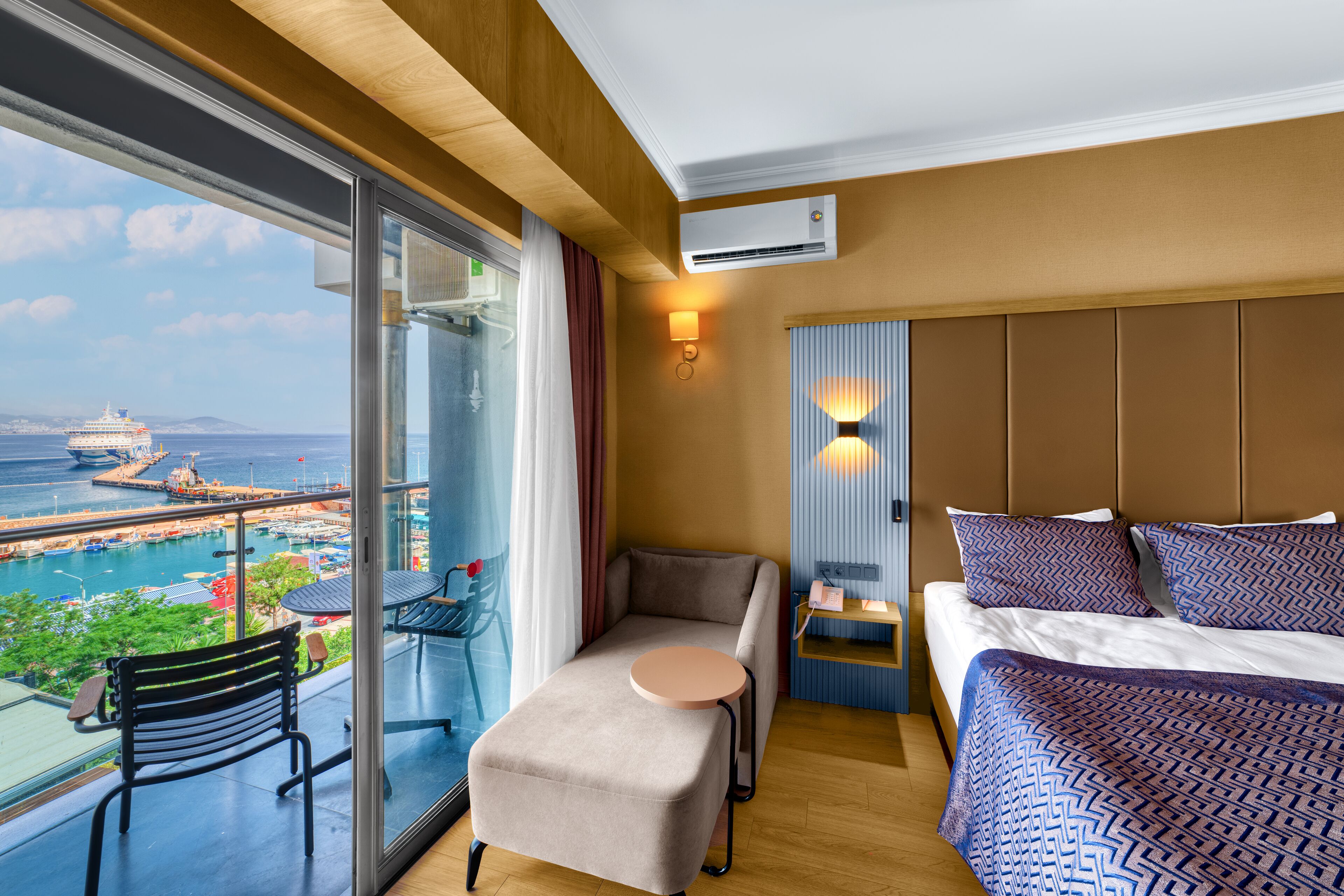 Une chambre d’hôtel avec un lit, une petite table, une chaise et une vue sur un navire de croisière et le port.