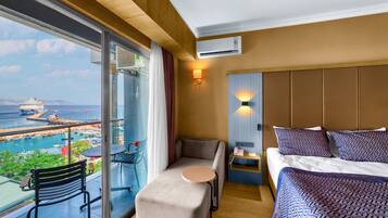 Une chambre d’hôtel avec un lit, une petite table, une chaise et une vue sur un navire de croisière et le port.