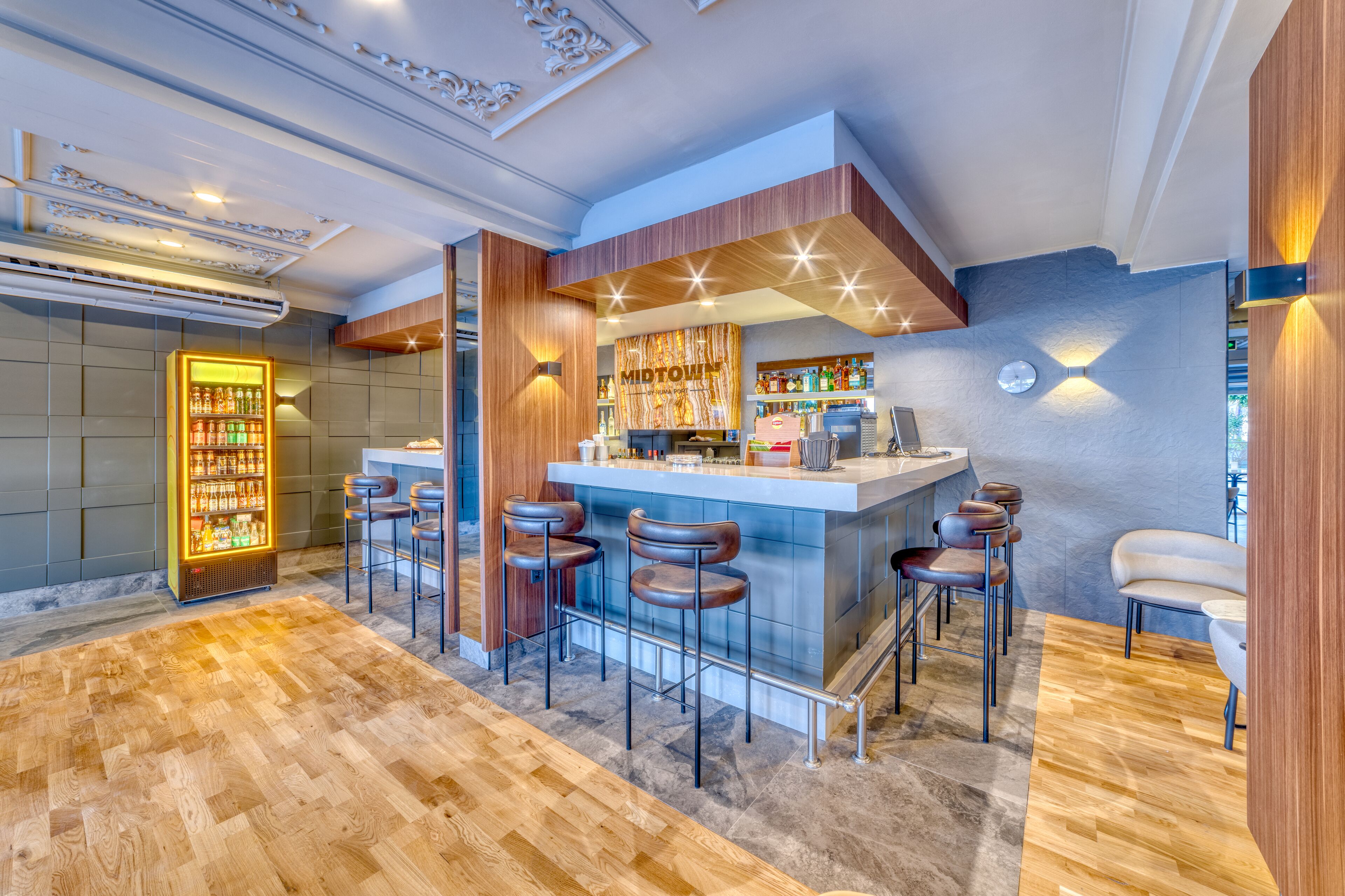 Un espace bar moderne doté d’un comptoir en marbre, de tabourets de bar et d’un mini-bar.
