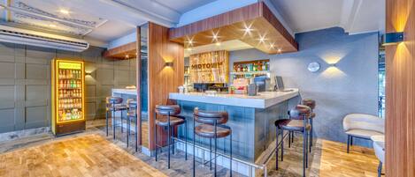 Un espace bar moderne doté d’un comptoir en marbre, de tabourets de bar et d’un mini-bar.