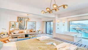 A modern hotel room with a large bed, a sitting area with a sofa and coffee table, a balcony with a view of the sea, and a bathtub. - Numa Port Hotel (Alanya)