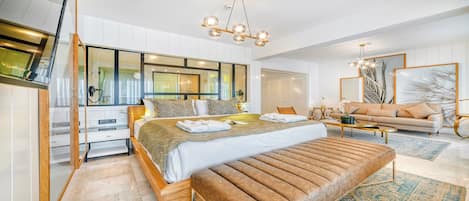 Ett modernt hotellrum med en stor säng, en soffa, ett soffbord och en TV.