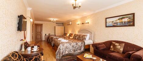 A hotel room with a bed, two bedside tables, a sofa, a coffee table, and a TV mounted on the wall.