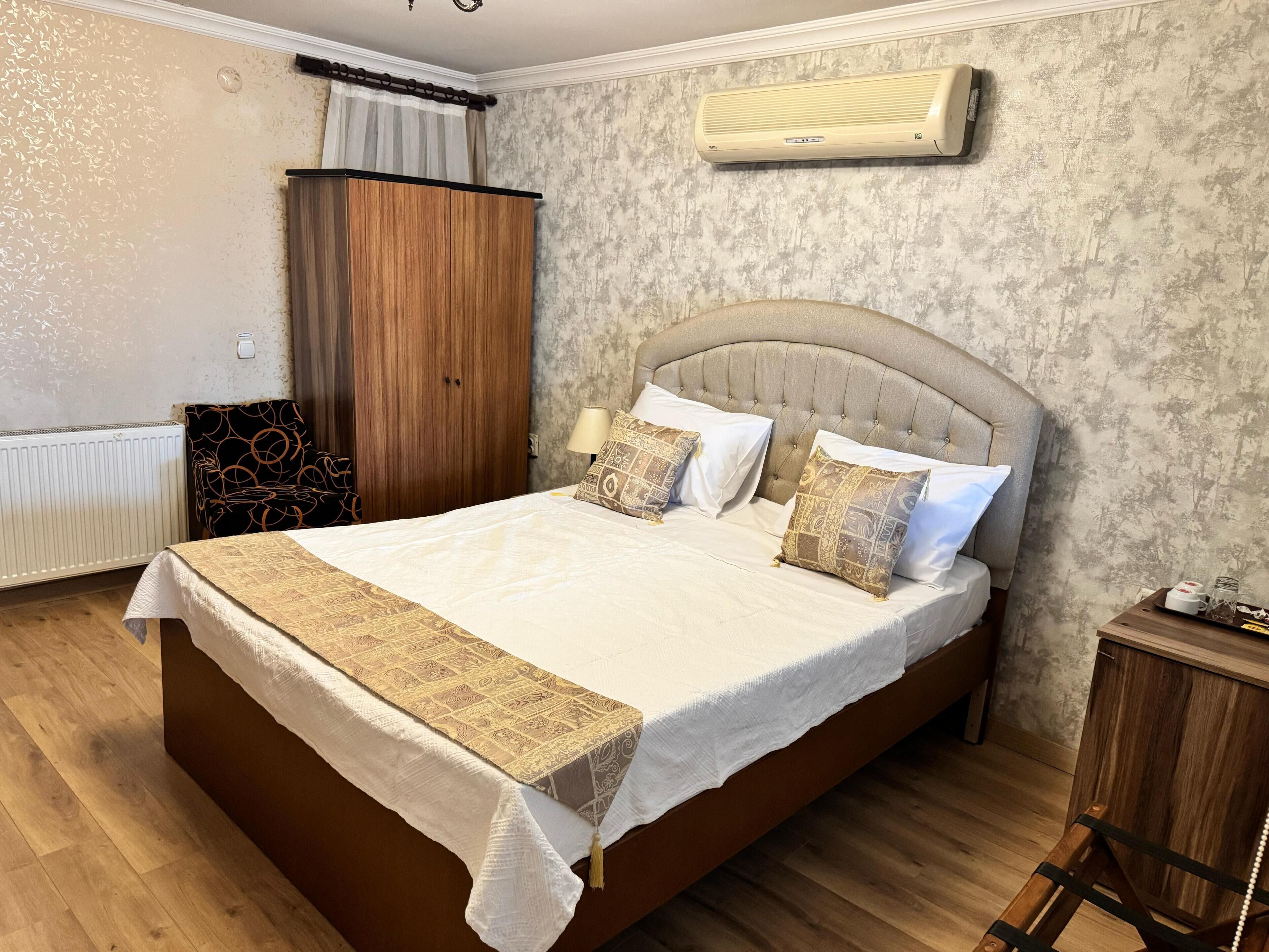 Un dormitorio con una cama grande, un armario, aire acondicionado y una silla.