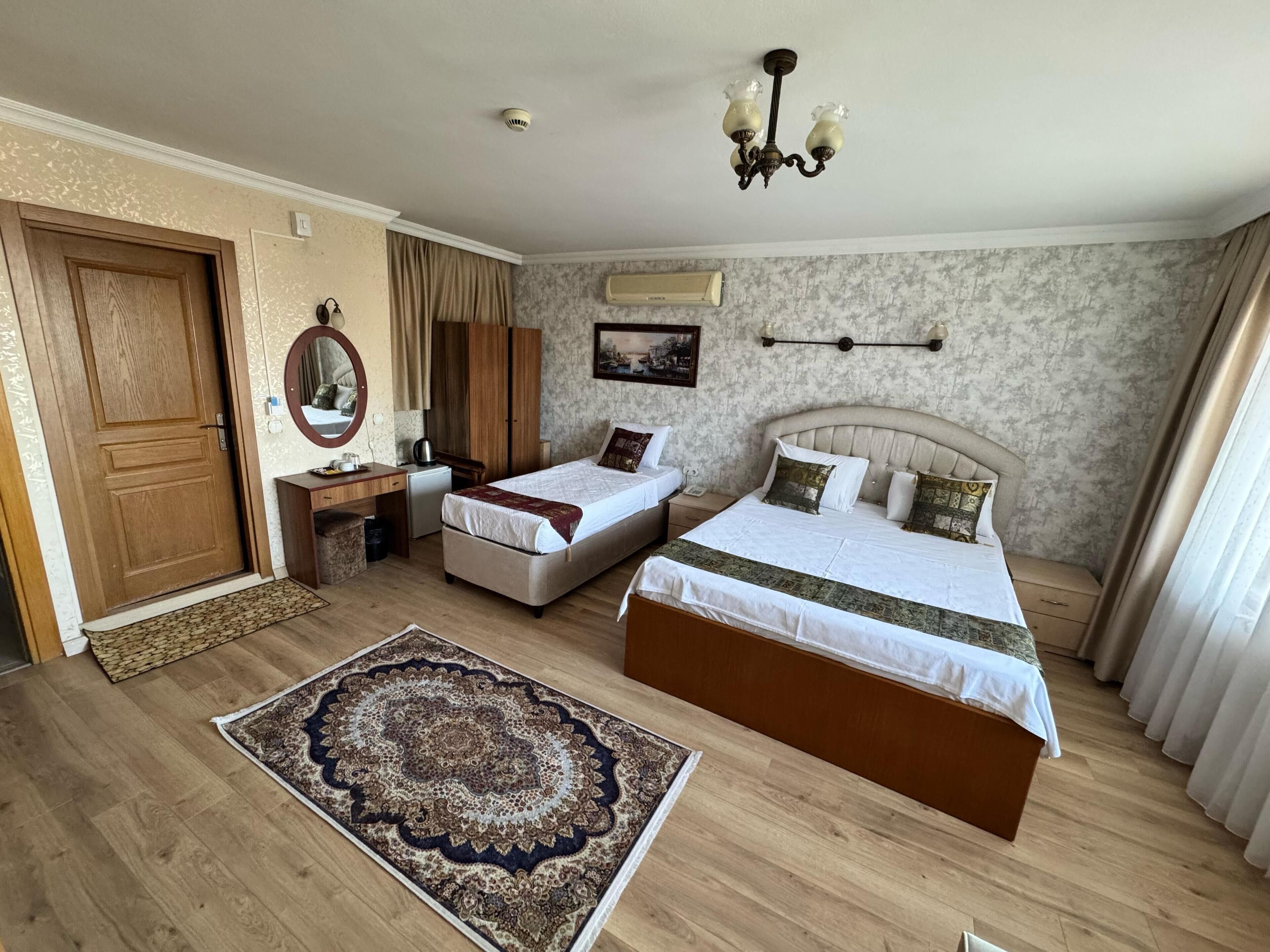 Habitación de hotel con dos camas, un escritorio, un armario, un espejo y una araña.