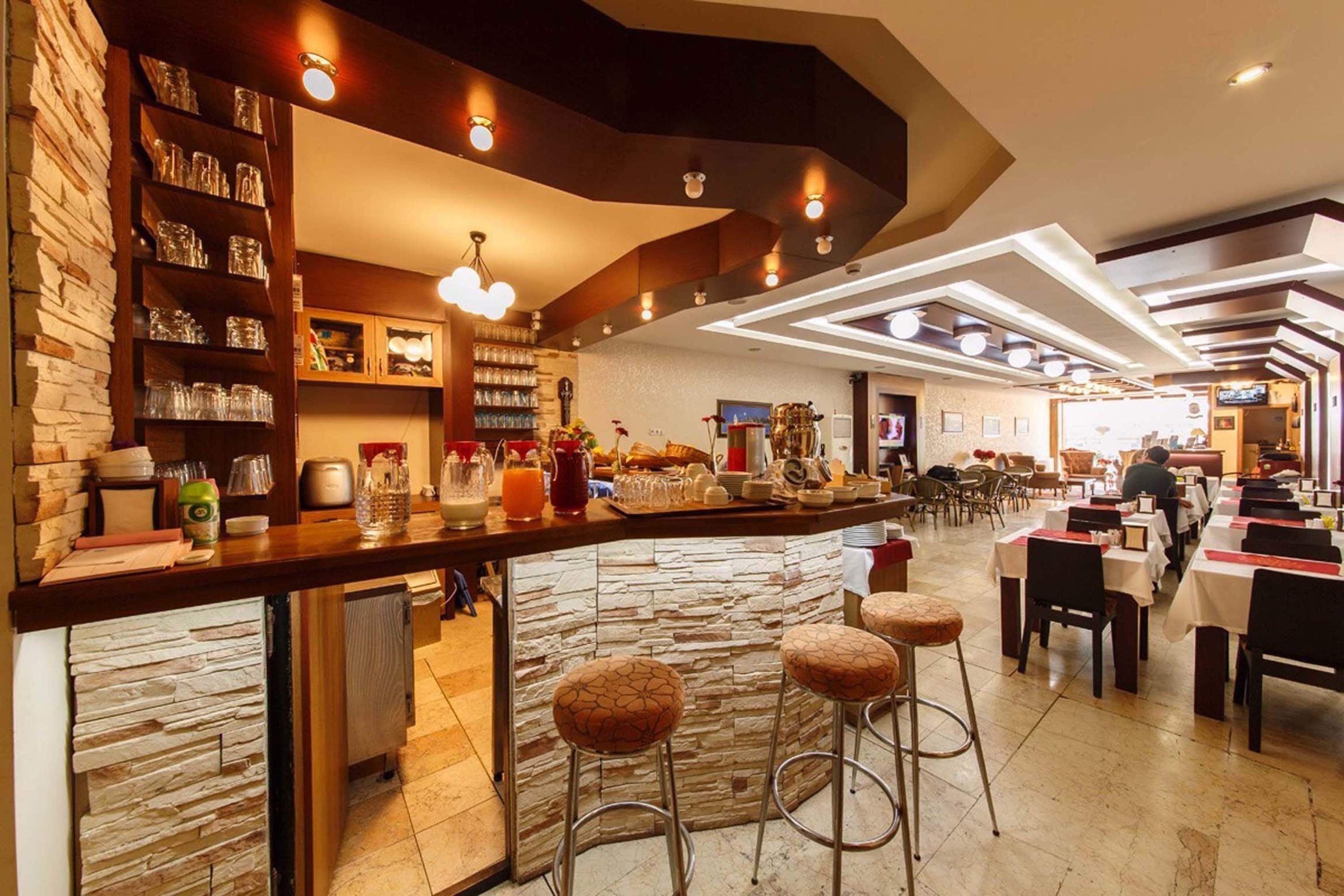 A modern restaurant with a stone bar, high chairs, and a variety of dining tables and chairs.