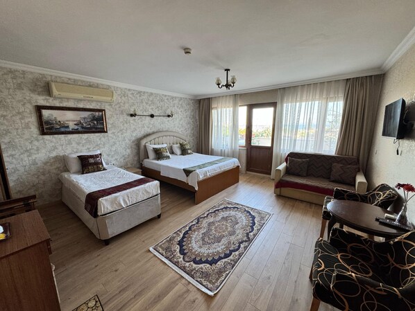 A bedroom with two single beds, a sofa, a TV, and a large window. - Ipekyolu Hotel (Istanbul)