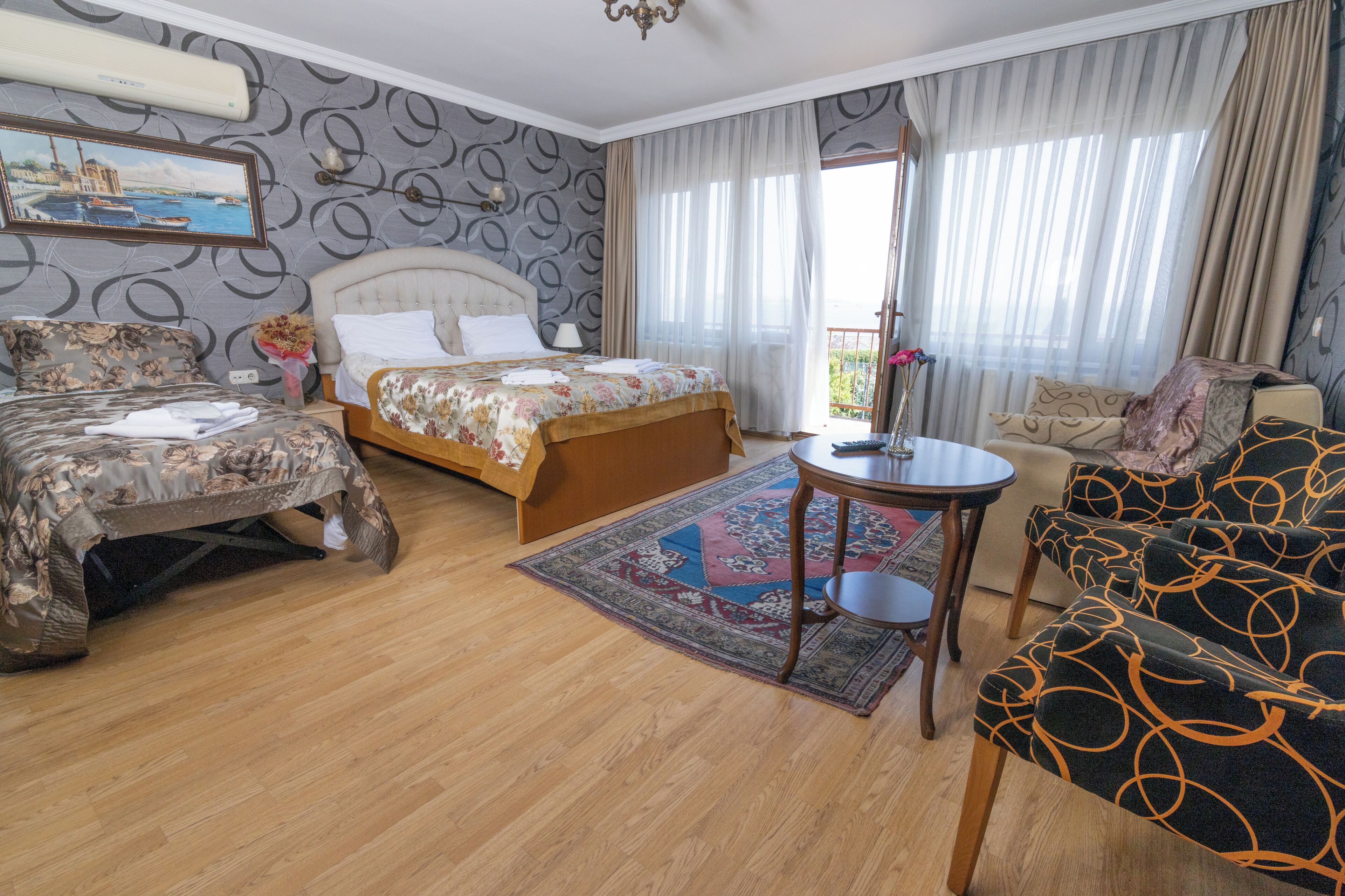 Een hotelkamer met een bed, een bank, een klein tafeltje en uitzicht op het landschap.