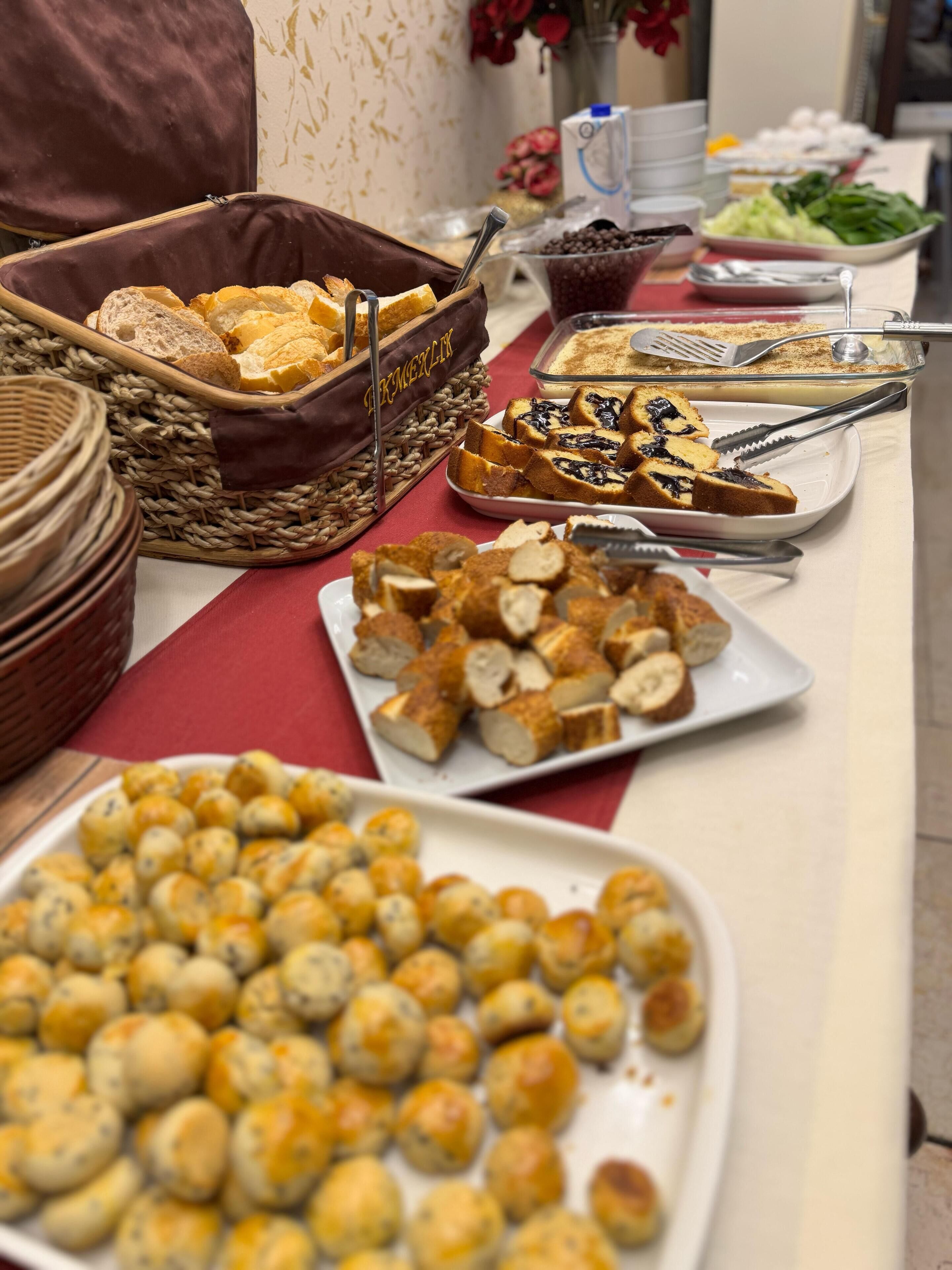 A buffet table with various food items including bread, pastries, and a variety of dishes.
