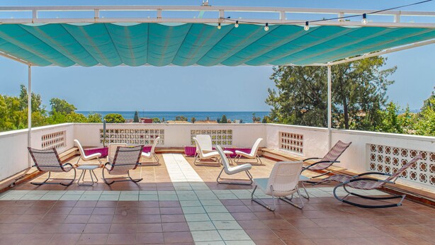Un espace extérieur aménagé, abrité et doté de chaises, offrant une vue sur la mer.