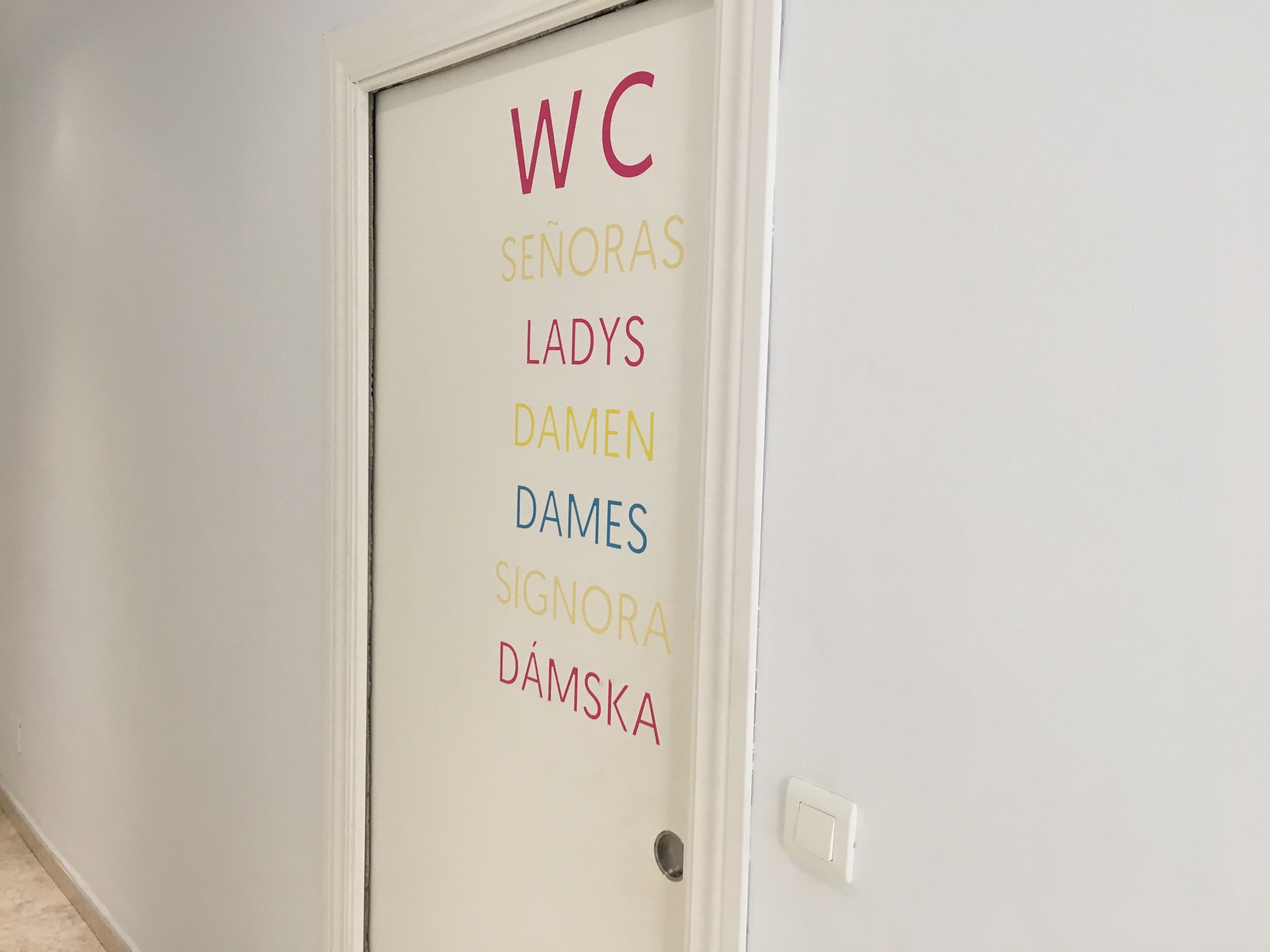 Una puerta con indicaciones para inodoro, señoras, damas, signora y Damska.