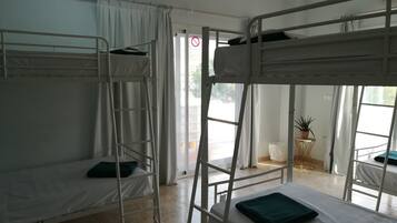 Un dormitorio con literas, una escalera, una mesita con una planta y vistas al exterior.