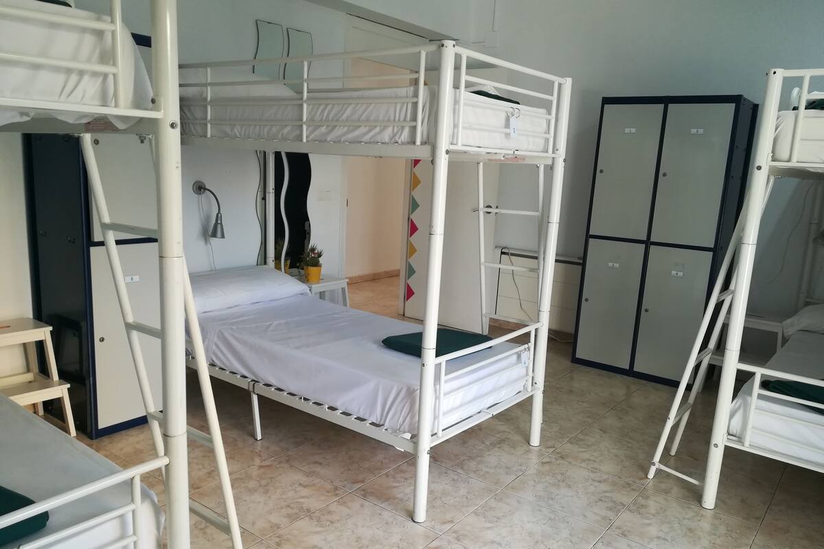 Ein Schlafsaalzimmer mit Etagenbetten, einem Schreibtisch, einem Stuhl und einem Kleiderschrank.