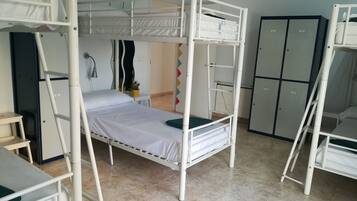 A dormitory room with bunk beds, a desk, a chair, and a wardrobe.