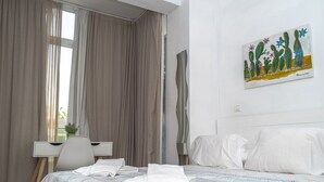 Une chambre d’hôtel avec un lit, un bureau et un tableau représentant des cactus accroché au mur.