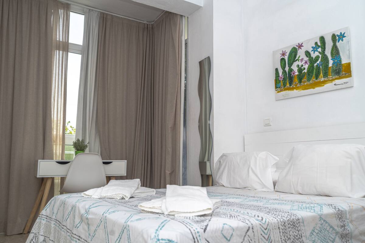 Ein Hotelzimmer mit einem Bett, einem Schreibtisch und einem Bild von Kakteen an der Wand.